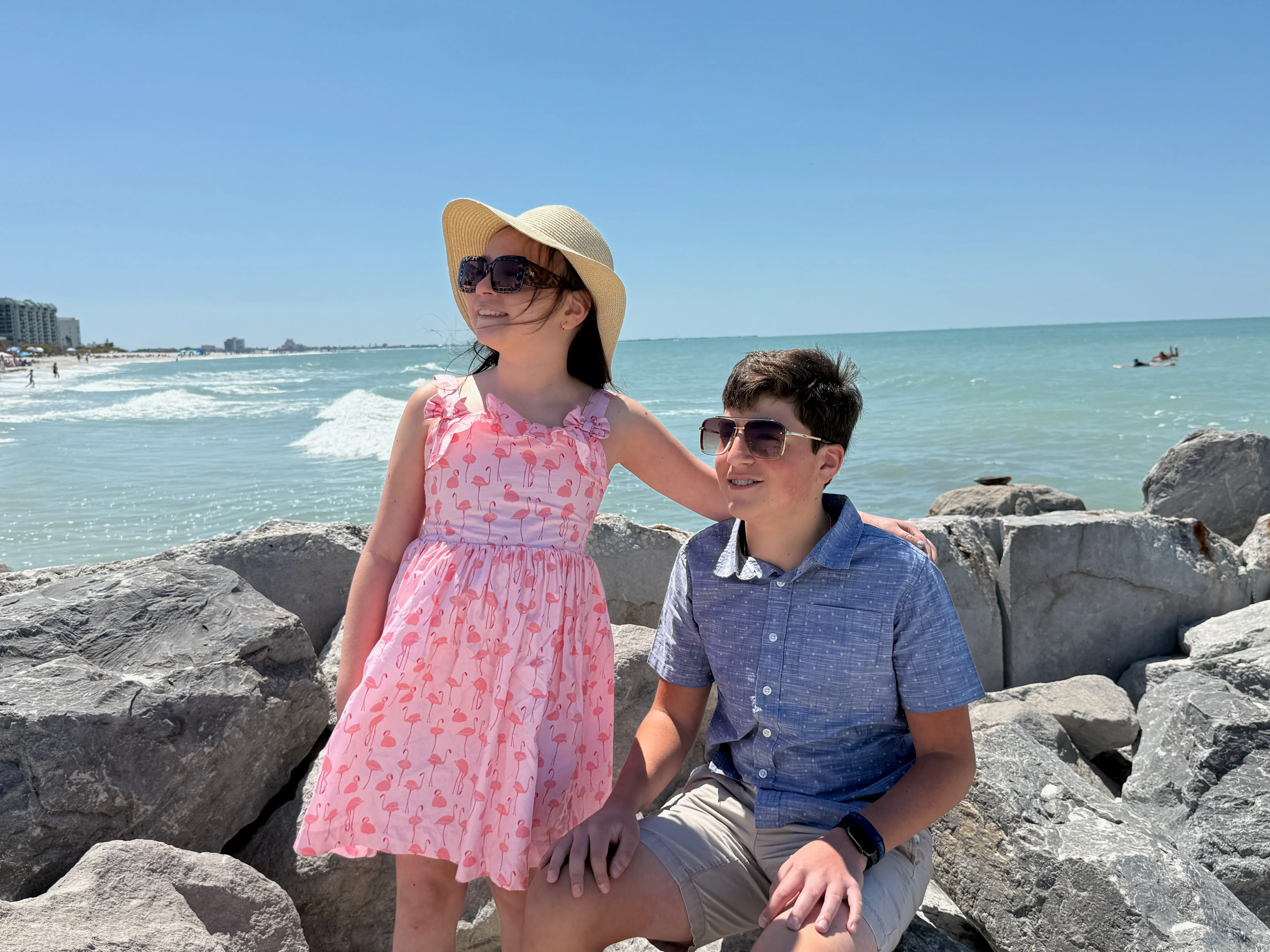 Two children of the SunRay Vending family smiling on the rocks by the Gulf of Mexico in Tampa Bay